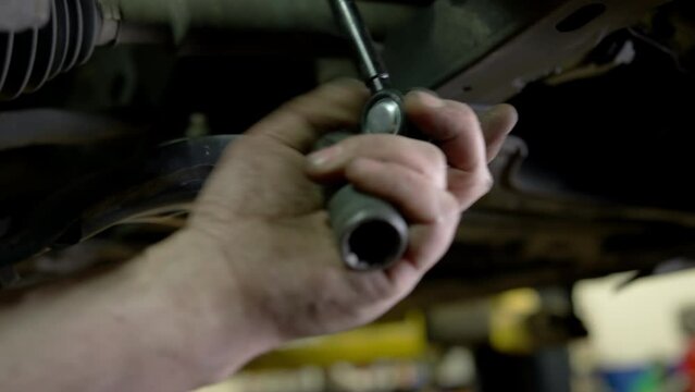 Car mechanic at repair service station inspecting car suspension detail