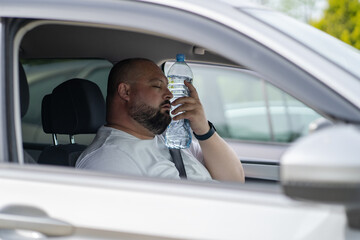 Exhausted overweight man driver suffering from heat inside car with broken air conditioner touch...