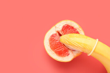 Banana with condom and half of grapefruit on red background. Sex concept