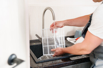 A man flushes the air cleaner filter from the air conditioner.