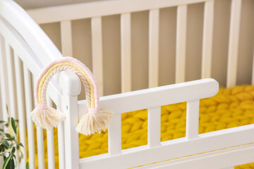Obraz na płótnie Canvas Baby crib with toy in light bedroom, closeup
