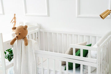 Fototapeta na wymiar Baby crib with toy bear in light bedroom