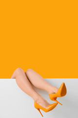 Female legs in stylish high heels on yellow background