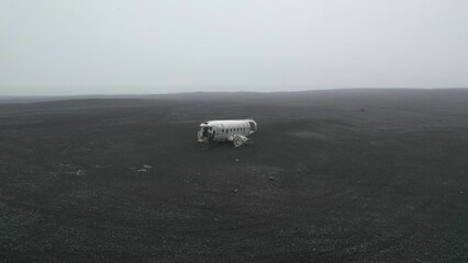 Aerial shot of an old plane wreck in the middle of a field on a foggy weather