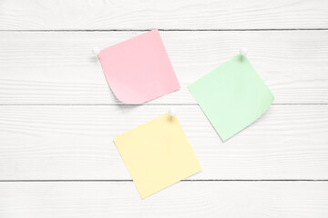 Sticky notes with pins on white wooden background