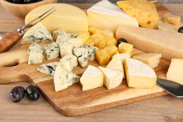 Board with pieces of tasty cheese on table