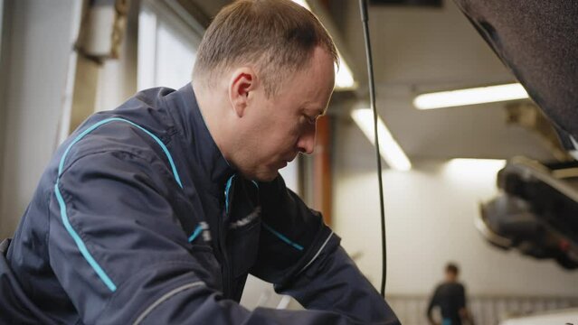 Mechanic is repairing an engine in the auto repair. The young auto mechanic dismantles the opposing engine for diagnosis and repair at the stand in the workshop. Auto mechanic working in garage