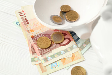 Broken piggy bank with money on white wooden background. Concept of bankruptcy