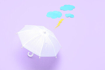 Composition with umbrella, paper clouds and lightning on lilac background