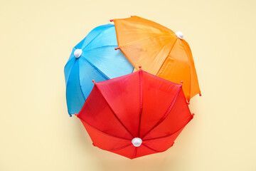 Different mini umbrellas on pale yellow background