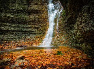 A small waterfall in rautal close to jena in thuringia at autumn - obrazy, fototapety, plakaty