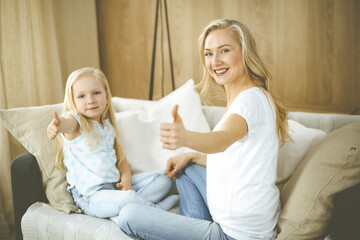 Happy family. Blonde young mother playing and hugging with her cute daughter. Motherhood concept.