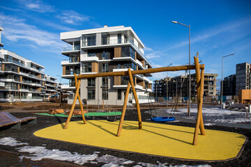Fototapeta na wymiar View of public park with newly built modern block of flats in winter/spring