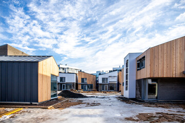 Naklejka premium A group of houses in the same style. Trendy modern barnhouse style houses. bright blue sky