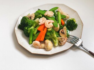High-angle view of fried mixed vegetables with shrimp served on a white plate