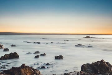 Rocky peaks of tall mountains hiding in the clouds with the golden sunrise in the background