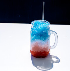 Delicious Red, White and Blue Hawaiian Shave Ice, Shaved Ice or Snow cone dessert in a clear Mason Jar with copy space.