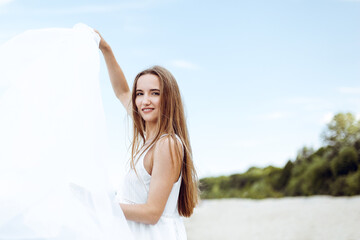 Happy smiling woman in free happiness bliss on ocean beach standing with open hands. Portrait of a multicultural female model in white summer dress enjoying nature during travel holidays vacation outd