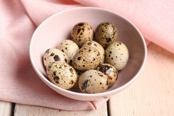 Bowl with fresh quail eggs on table