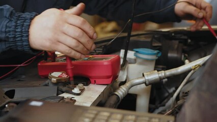 Services car engine machine concept, Automobile mechanic repairman hands checking a car engine automotive workshop with digital multimeter testing battery, car service and maintenance.