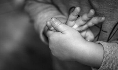 Grayscale shot of a child's hands on a blurred background