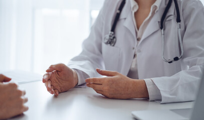 Doctor and patient discussing current health examination while sitting at the desk in clinic office, closeup. Medicine concept.