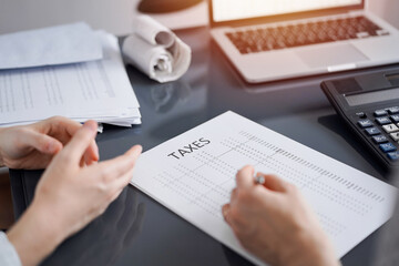 Woman accountant using a calculator and laptop computer while counting taxes for a client. Business...