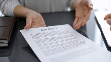 Business people sitting and discussing contract in office, closeup. Partners or lawyers working together at meeting before signing papers. Teamwork and partnership.