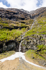 Beautiful natural long and majestic Glacier waterfall in Norway mountains. Covered with trees forming a forest with beautiful wildlife and nature.