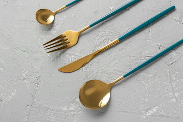 Golden set of cutlery with green handles on grey background