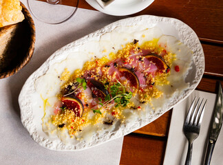 Tasty fish dish - cod carpaccio with fresh figs on plate