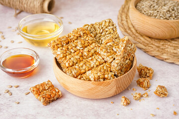 Bowls with tasty kozinaki, honey and sunflower seeds on white background