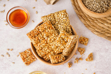 Bowls with tasty kozinaki, honey and sunflower seeds on white background