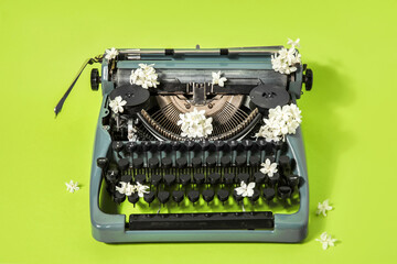 Vintage typewriter with white lilac on green background