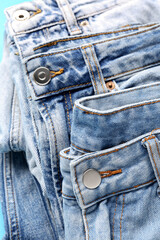 Different stylish jeans as background, closeup