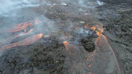 Volcanic eruption with glowing orange lava flow surrounded by a pool of bubbling magma