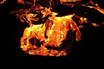 Volcanic eruption with glowing orange lava flow surrounded by a pool of bubbling magma
