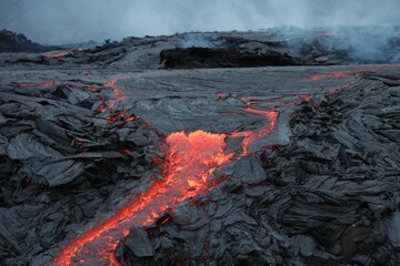 Volcanic eruption with glowing orange lava flow surrounded by a pool of bubbling magma