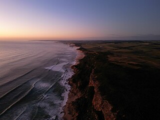 Aerial view of sea waves breaking beach during sunset