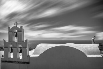 Grayscale shot of a man on the roof of a church on Santorini Island, Greece