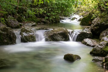 Long exposure of a rocky river flowing surrounded by forest vegetation