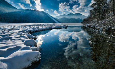 Beautiful lake reflecting the cloudy blue sky on a sunny winter day perfect for wallpapers