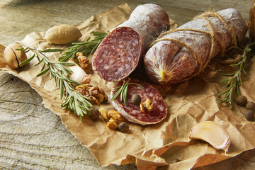 Italian salami wih sea salt, rosemary, garlic and nuts on paper. Rustic style. Close up. - 612566598