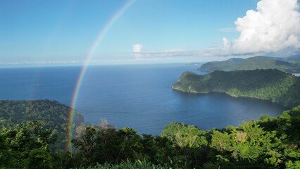 Naklejka na ściany i meble Mesmerizing landscape of a tropical lush-forested island under a double rainbow