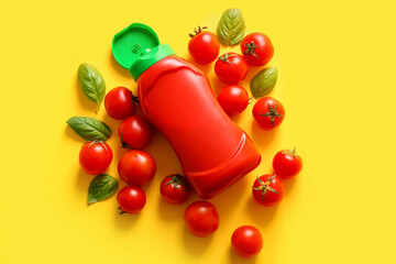 Bottle of ketchup and tomatoes on yellow background