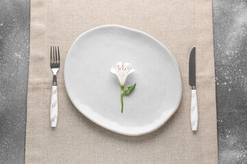 Silver fork with knife, plate and alstroemeria on grey grunge table