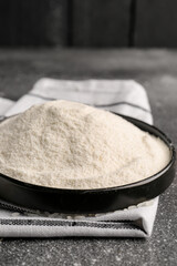 Plate with rice and flour on grunge black table near wall
