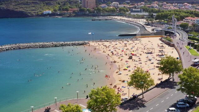 Drone view of Machico beach with people havig fun on a summer day, Madeira, Portugal