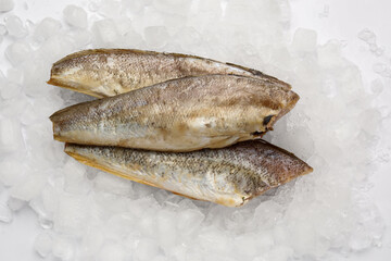 Raw codfish with ice cubes on white background