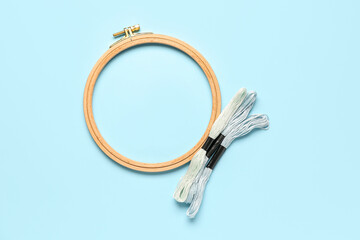 Wooden embroidery hoop with mouline threads on blue background